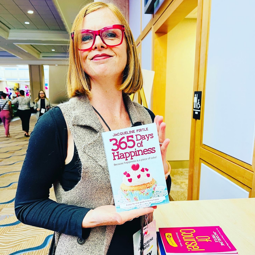 Jacqueline Pirtle holding 365 Days of Happiness book at a speaking event — bestselling author and energy reader