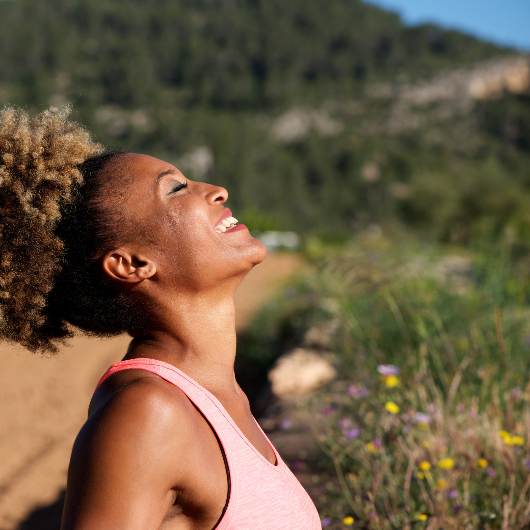 Woman with eyes closed smiling in a natural setting